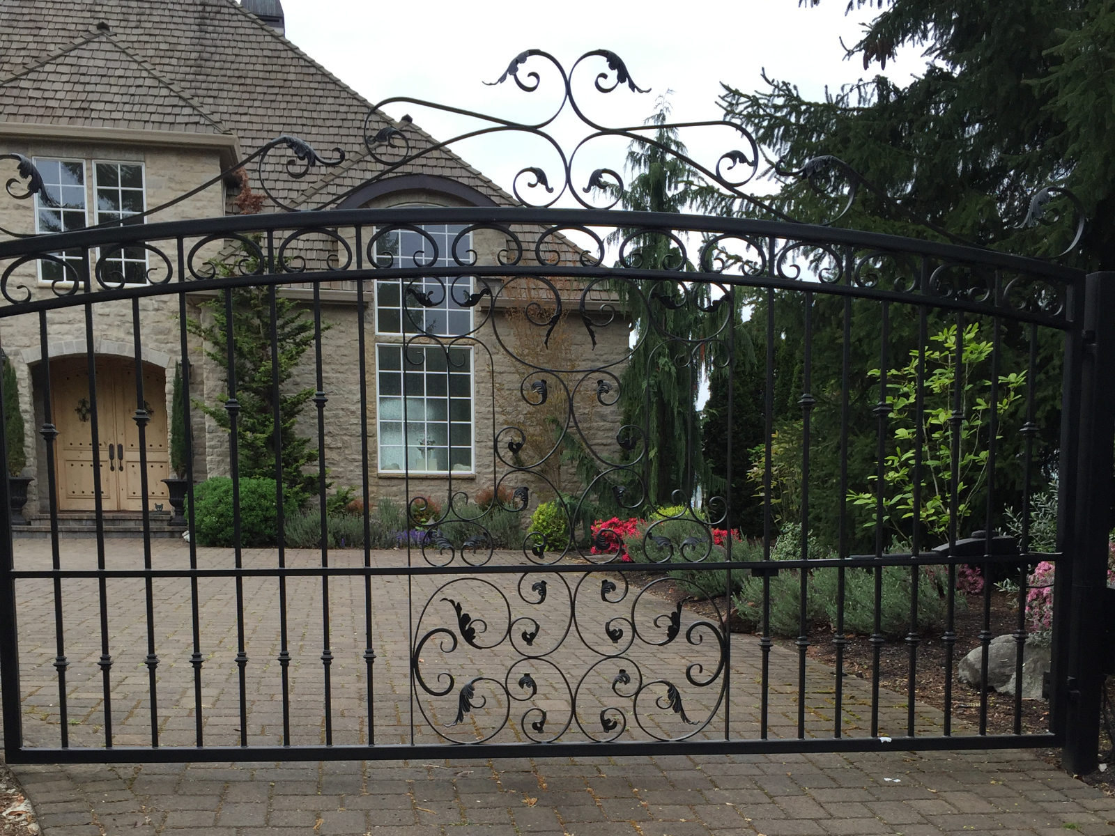 Black ornate wrought iron driveway gate with arched top | Chip and Dale's Iron Works